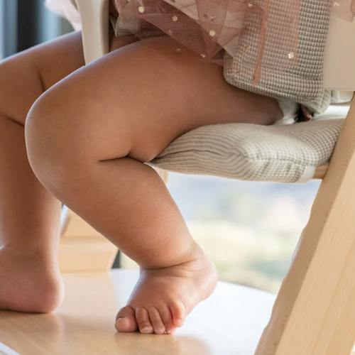 detalle de calidad de la trona tripp trapp en la que se aprecia la madera de haya y la posición ergonómica de los pies del bebé apoyados en el reposapies